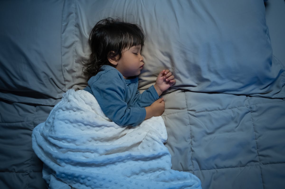 Toddler baby sleeping on a bed at night